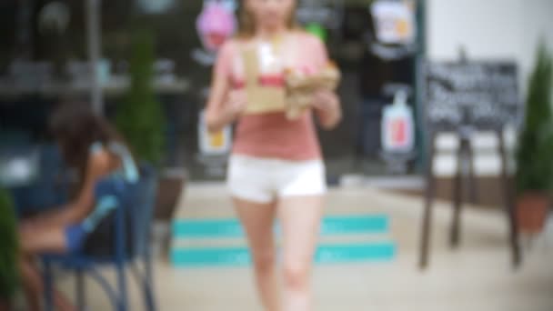 Дівчина залишає кондитерський магазин з круасанами, пончиком і коктейлями для компанії друзів. розмивання, крупним планом. 4k, повільний рух. зльоту — стокове відео