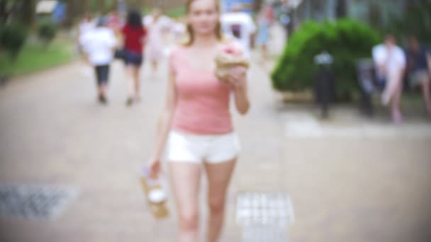 Девушка выходит из кондитерской с круассанами, пончиком и кофе для компании друзей. размыто, крупным планом. 4К, замедленная съемка. take-away — стоковое видео