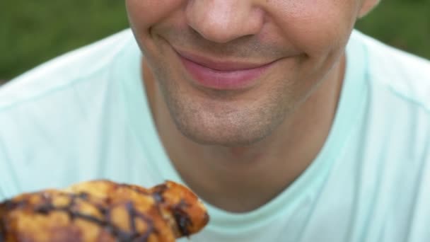 Ένας όμορφος άνδρας φαίνεται χαρούμενος τρώγοντας νόστιμα κρουασάν. γκρο πλαν των χειλιών. 4 k αργή κίνηση — Αρχείο Βίντεο