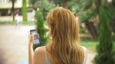 izlerken memnun kız sokakta bir kafede oturup telefon