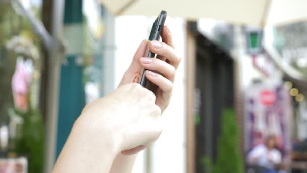 Γυναικεία χέρια κρατάει ένα smartphone στο δρόμο αναστρέφει μέσα από την οθόνη. — Αρχείο Βίντεο