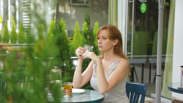 Het meisje is het drinken van thee met zithoek in een zomerterras. Transparant glas. — Stockvideo