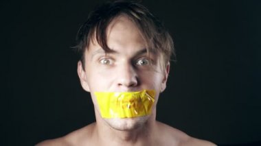 Genç adam bantlanmış ağızlı. siyah bir arka plan üzerinde. 4k.