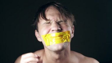 Genç adam bantlanmış ağızlı. siyah bir arka plan üzerinde. 4k.