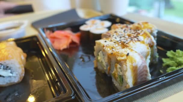 Jonge vrouw in café eten sushi met stokjes. 4k, close-up. — Stockvideo