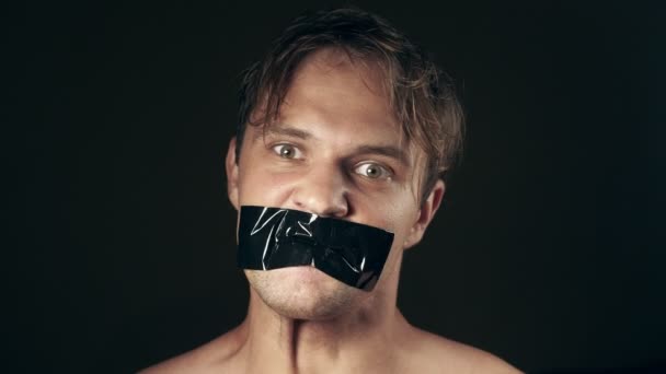 Junger Mann mit verklebtem Mund. auf schwarzem Hintergrund. 4k. — Stockvideo