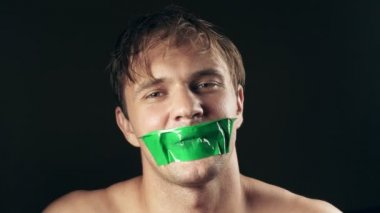 Genç adam bantlanmış ağızlı. siyah bir arka plan üzerinde. 4k.