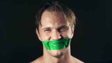 Genç adam bantlanmış ağızlı. siyah bir arka plan üzerinde. 4k.