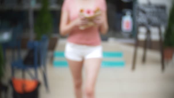 A menina deixa a pastelaria com croissants e um donut para uma companhia de amigos. Desfoque, close-up. 4k, câmera lenta, take-away — Vídeo de Stock