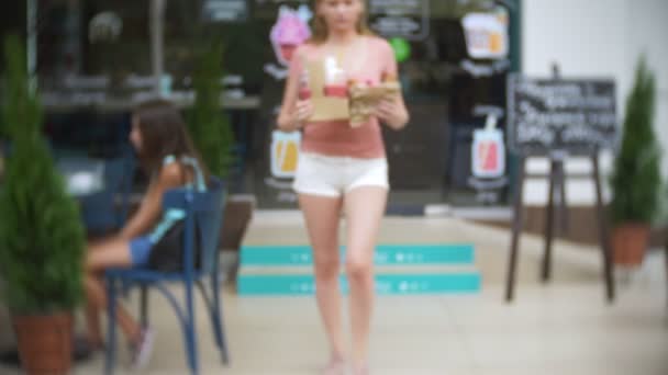 Dívka opustí cukrárna s croissanty, kobliha a smoothie pro společnost přátel. rozostření, detail. 4k, zpomalené. s sebou — Stock video
