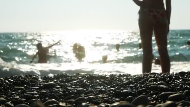 Silhouette dell'irriconoscibilità delle persone che riposano sulla spiaggia durante il tramonto . — Video Stock