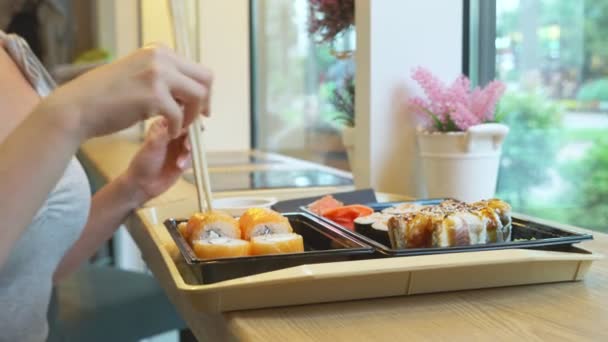 Mladá žena v kavárně s hůlkami jíst sushi. 4k, detail. — Stock video