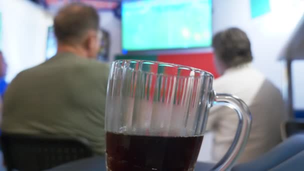 Titta på fotbollsmatch på TV vid lokala pub. Mat, öl. en mugg med öl i fokus, en Tv-skärm med en sändning av en fotboll oskärpa. 4k — Stockvideo