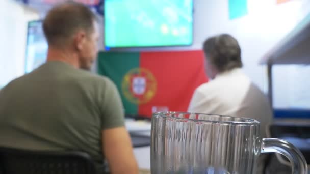 Yerel barda televizyonda futbol maçı izliyor. Gıda, bira. bir kupa bira odak ile bir Tv ekranında bir yayın bir futbol ile bulanıklık. 4k — Stok video