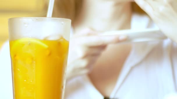 Close-up, 4k, a woman in a cafe drinking cold sea-buckthorn tea from a straw — Stock Video