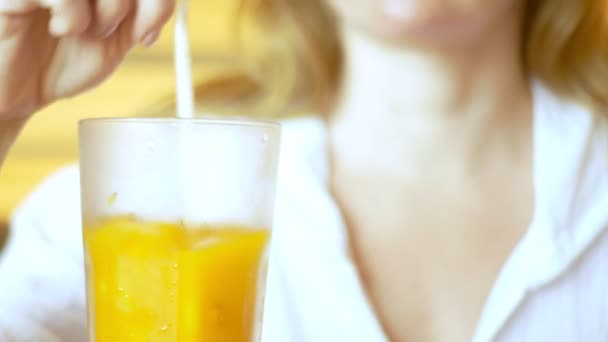 Close-up, 4k, een vrouw in een café koude zee-duindoorn thee drinken uit een rietje — Stockvideo
