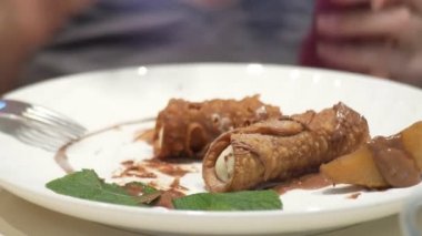 Kapatın. Cannoli armut ve çikolata ile birisi bir restoranda tatlı yiyor. 4k