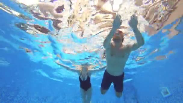 4k. Vista bajo el agua. Un par de hombres y mujeres nadando bajo el agua juntos . — Vídeos de Stock