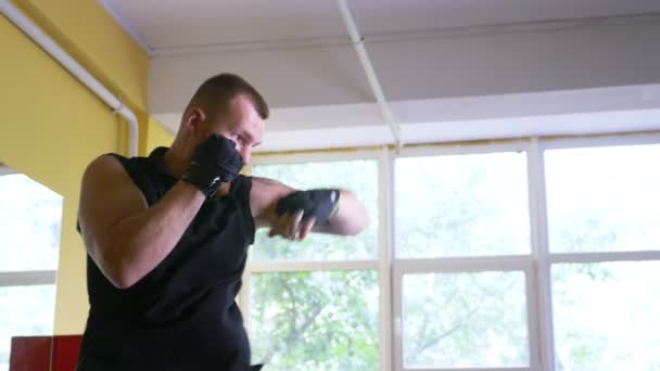 Un atleta boxeador profesional entrena en la sala de artes marciales. joven europeo en el gimnasio, con una camiseta con un entrenador de inscripción. 4k, cámara lenta , — Vídeos de Stock