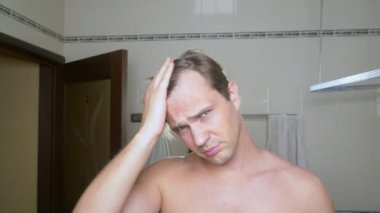 Genç çekici adam uzaklaşıyorsun saç çizgisi banyoda olup olmadığını denetler. Kellik