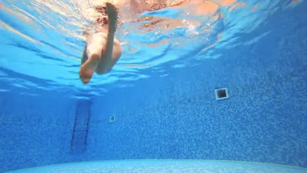 4k. Blick unter Wasser. Frau im schwarzen Badeanzug schwimmt im Pool. — Stockvideo