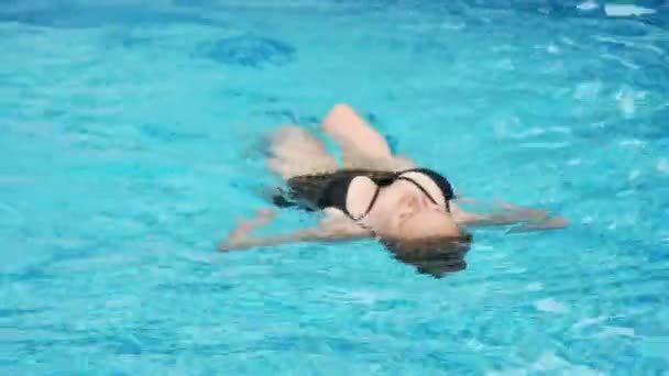 Sexy žena v černých plavkách plave v bazénu. Zpomalený pohyb. 4k. — Stock video