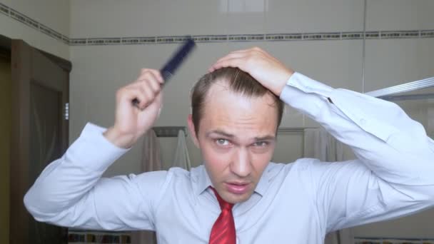 Homem atraente jovem inspeciona uma linha de cabelo recuando no banheiro. Calvície — Vídeo de Stock