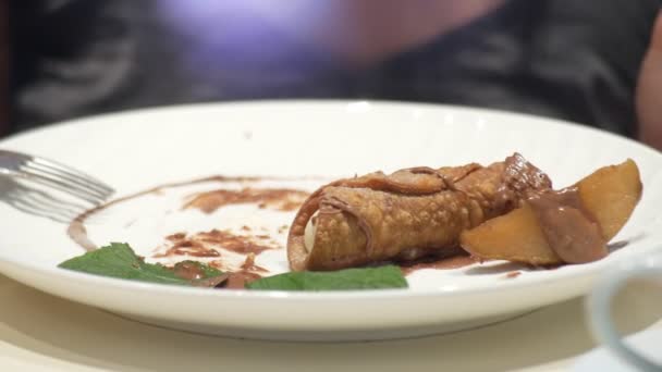 Perto. cannoli com pêra e chocolate, alguém come sobremesa em um restaurante. 4k — Vídeo de Stock