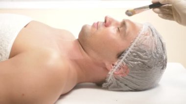 Yakışıklı erkekler yüz maskesi alma için spa terapisi. 4 k. ağır çekim. Bir güzellik uzmanı alımı