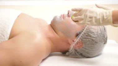 Yakışıklı erkekler yüz maskesi alma için spa terapisi. 4 k. ağır çekim. Bir güzellik uzmanı alımı
