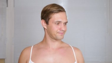 Yüz paketi olan garip adam. Genç bir adam bir ev bir ayna önünde yüz için kozmetik işlemler yapar. 4k