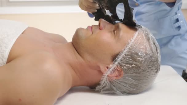 Terapia de spa para homens bonitos recebendo máscara facial. 4K. Movimento lento. Recepção de um cosmetologista — Vídeo de Stock