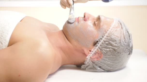 英俊的男人接收面膜的水疗治疗。4 k.慢动作。接待处的美容师 — 图库视频影像
