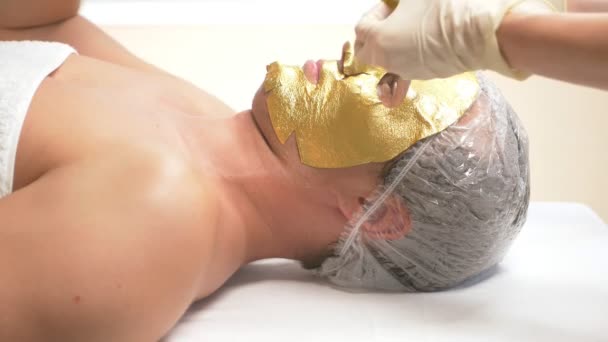 温泉療法によりハンサムな男性の顔のマスクを受信します スローモーション 美容師のレセプション 黄金のマスク — ストック動画