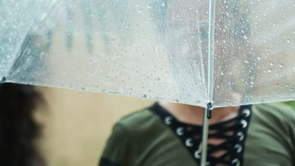 Silhueta de uma mulher de pé sob um guarda-chuva transparente durante uma chuva. 4k . — Vídeo de Stock