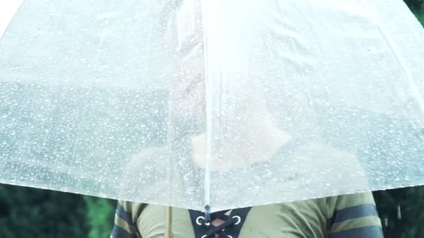 Silueta de una mujer de pie bajo un paraguas transparente durante una lluvia. 4k . — Vídeo de stock