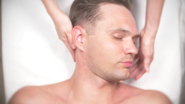 Un homme qui se fait masser le visage. Massez le visage et le cou. couché dans le bureau du kasmetologue. 4k, ralenti, vue de dessus — Video
