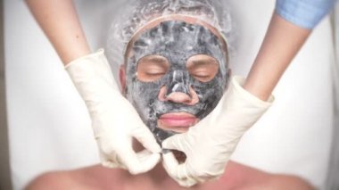 Yakışıklı erkekler yüz maskesi alma için spa terapisi. 4 k. ağır çekim. Bir güzellik uzmanı alımı