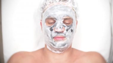 Yakışıklı erkekler yüz maskesi alma için spa terapisi. 4 k. ağır çekim. Bir güzellik uzmanı alımı