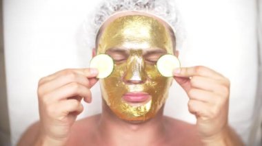 Yakışıklı erkekler yüz maskesi alma için Spa terapisi. 4 k. ağır çekim. Bir güzellik uzmanı alımı. altın maske