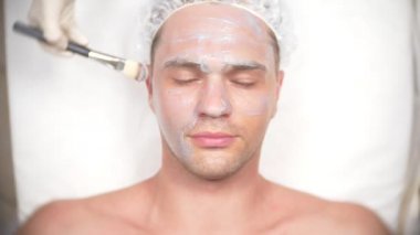 Yakışıklı erkekler yüz maskesi alma için spa terapisi. 4 k. ağır çekim. Bir güzellik uzmanı alımı