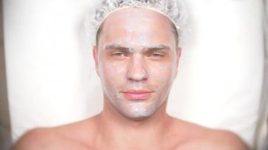 Yakışıklı erkekler yüz maskesi alma için spa terapisi. 4 k. ağır çekim. Bir güzellik uzmanı alımı