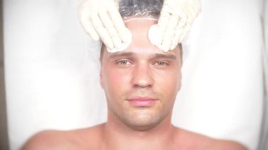 Yakışıklı erkekler yüz maskesi alma için spa terapisi. 4 k. ağır çekim. Bir güzellik uzmanı alımı