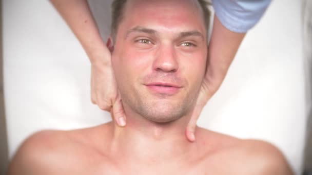 Dívka kosmetička sexuálně dotkne klienta, mladý pohledný muž, kterého jí čelit masáže v kanceláři lékaři. Ten člověk je překvapen. On je proti sexuálnímu obtěžování. 4k, pohled shora. Zpomalený pohyb — Stock video