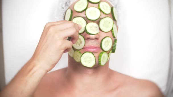 Seltsamer Mann mit Gesichtsmaske. Ein junger Mann macht kosmetische Eingriffe am Gesicht eines Hauses vor dem Spiegel. 4k, Gurkenmaske — Stockvideo