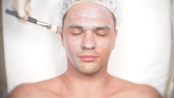 英俊的男人接收面膜的水疗治疗。4 k.慢动作。接待处的美容师 — 图库视频影像