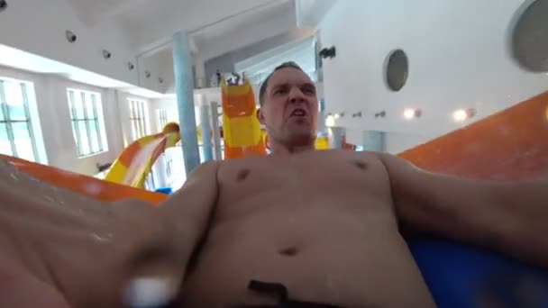 Vader en zoon afstamt van de glijbaan in het zwembad in het waterpark. in de pijp. 4k — Stockvideo