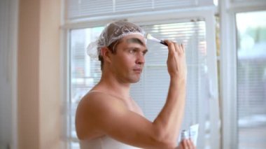 Yüz paketi olan garip adam. Genç bir adam bir ev bir ayna önünde yüz için kozmetik işlemler yapar. 4k