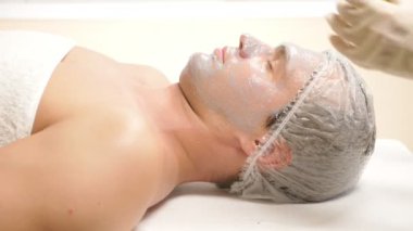 Yakışıklı erkekler yüz maskesi alma için spa terapisi. 4 k. ağır çekim. Bir güzellik uzmanı alımı.