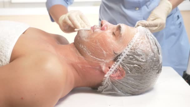 Terapia de spa para hombres guapos que reciben máscara facial. 4k. En cámara lenta. Recepción de un cosmetólogo — Vídeo de stock
